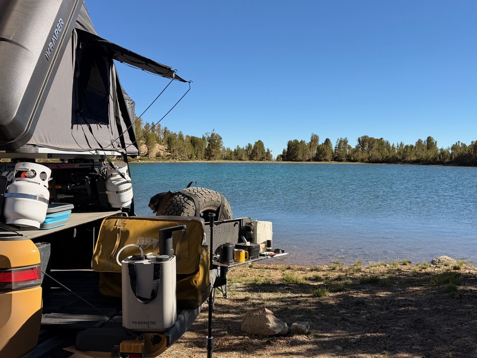 Camp kitchen set up from the rear of the Rivian beside a lake