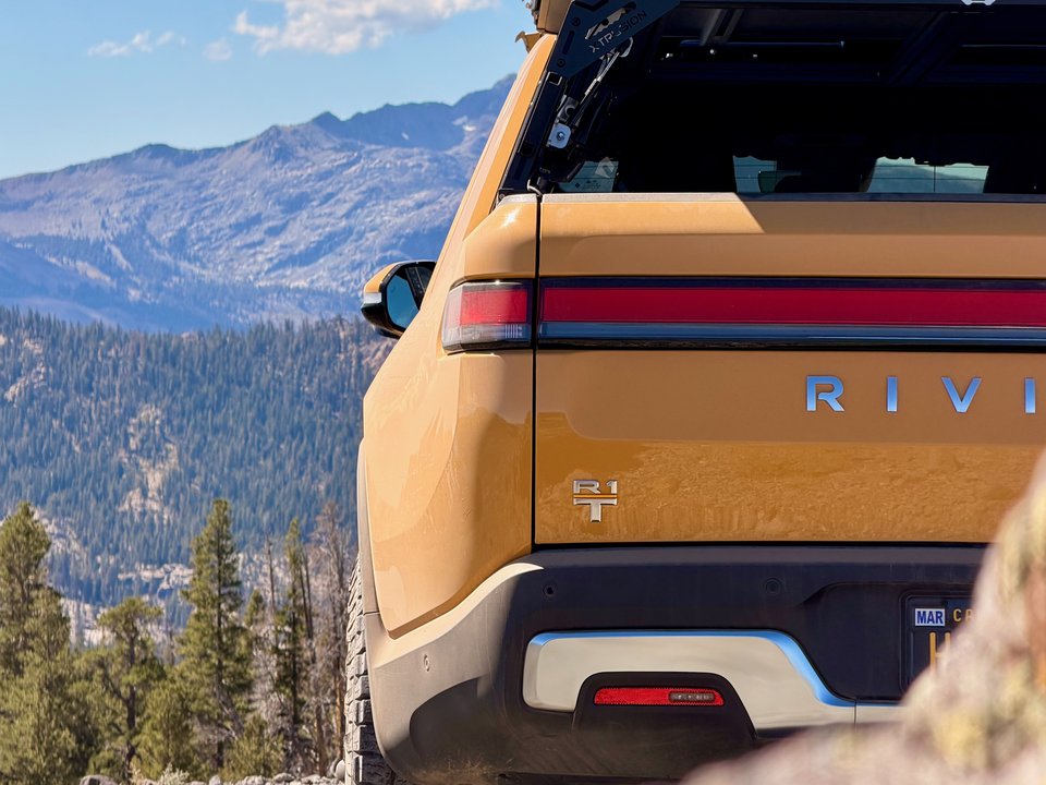 Compass Yellow Rivian R1T in front of snow-covered mountains