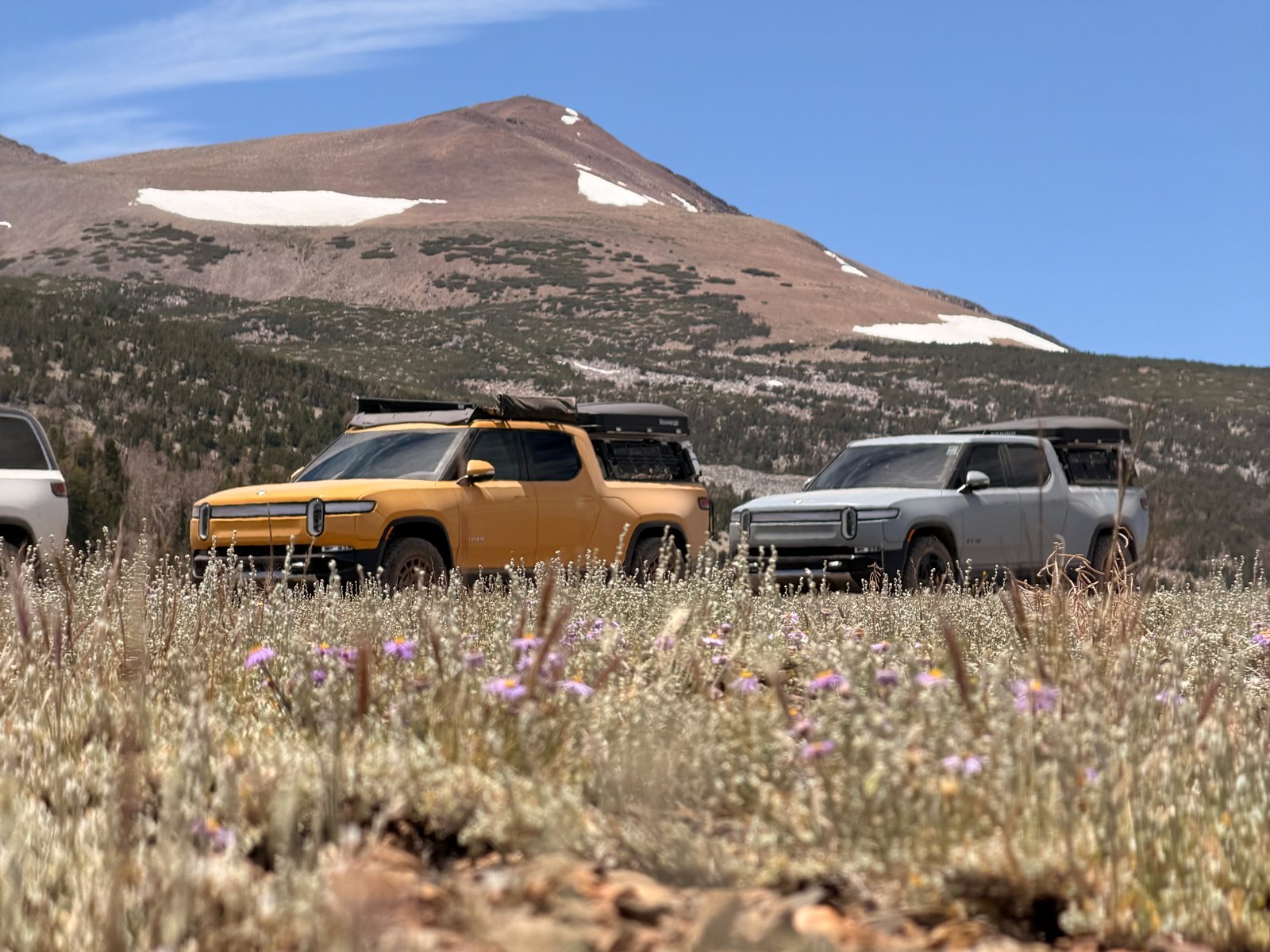 Rivian R1T with its rooftop tent in a broad mountain landscape