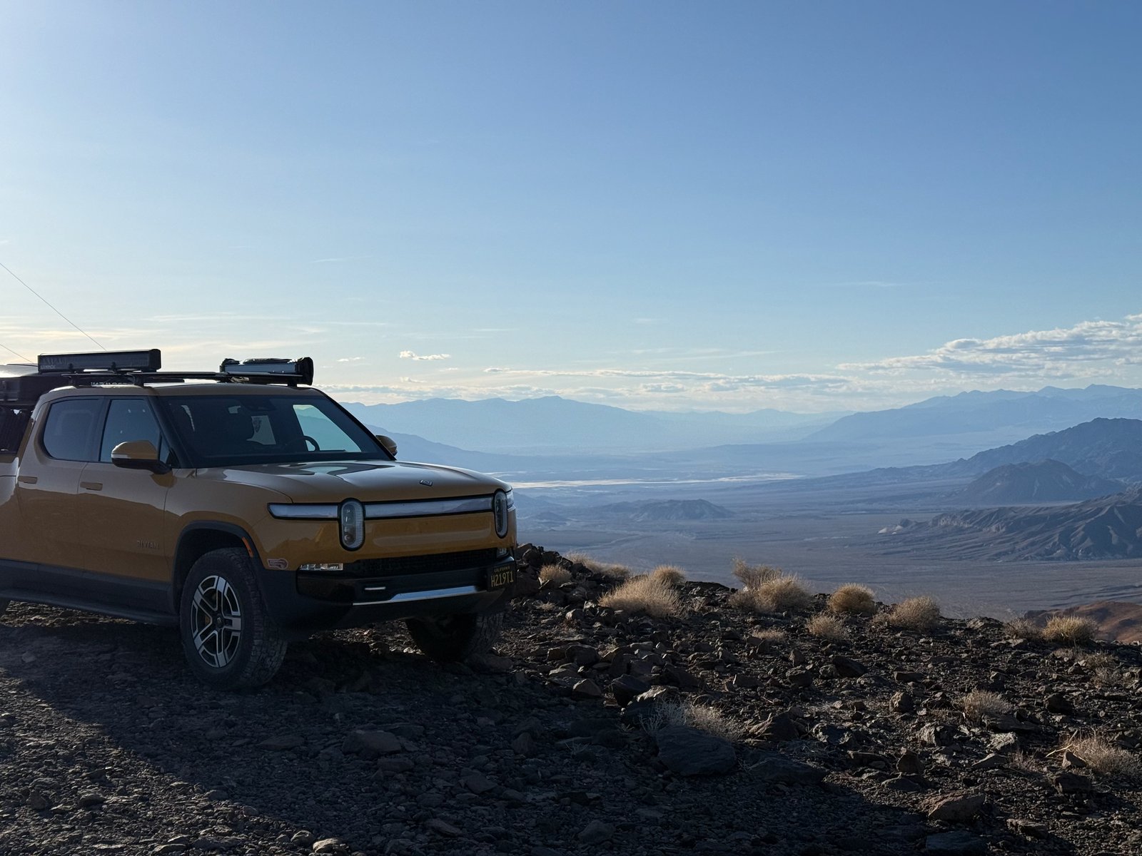 Rivian R1T parked on a rocky overlook above a desert valley