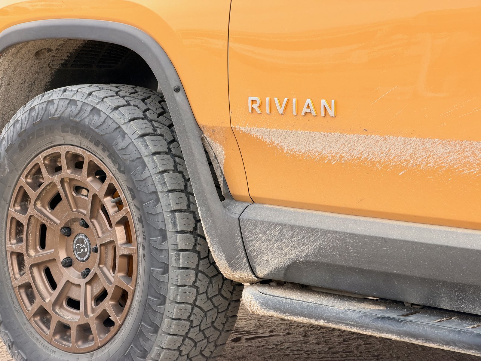 Bronze wheel, all-terrain tire, and rock slider on the Rivian